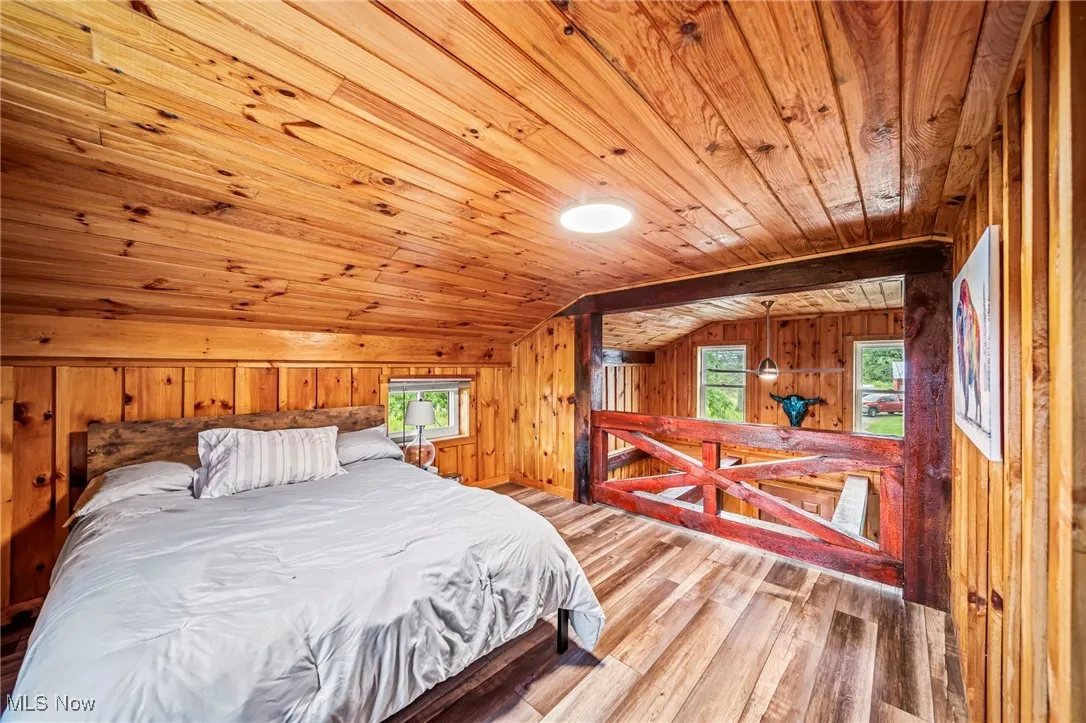 Bedroom featuring vaulted ceiling, hardwood / wood-style flooring, wooden walls, and wood ceiling