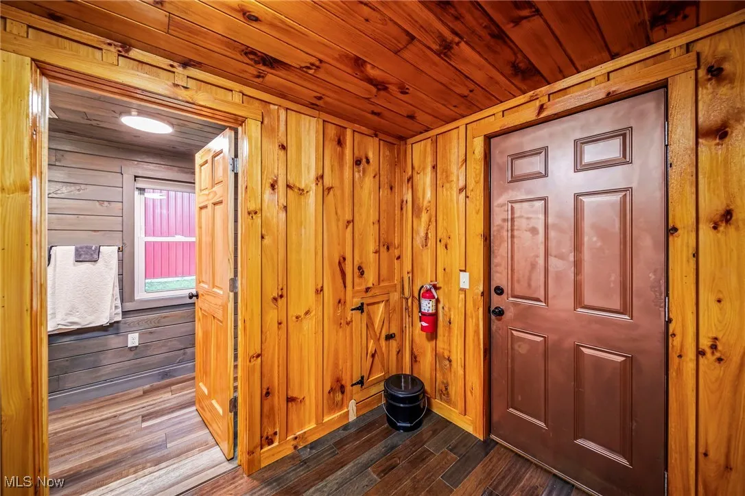 Foyer with dark wood finished floors, wood ceiling, and wooden walls