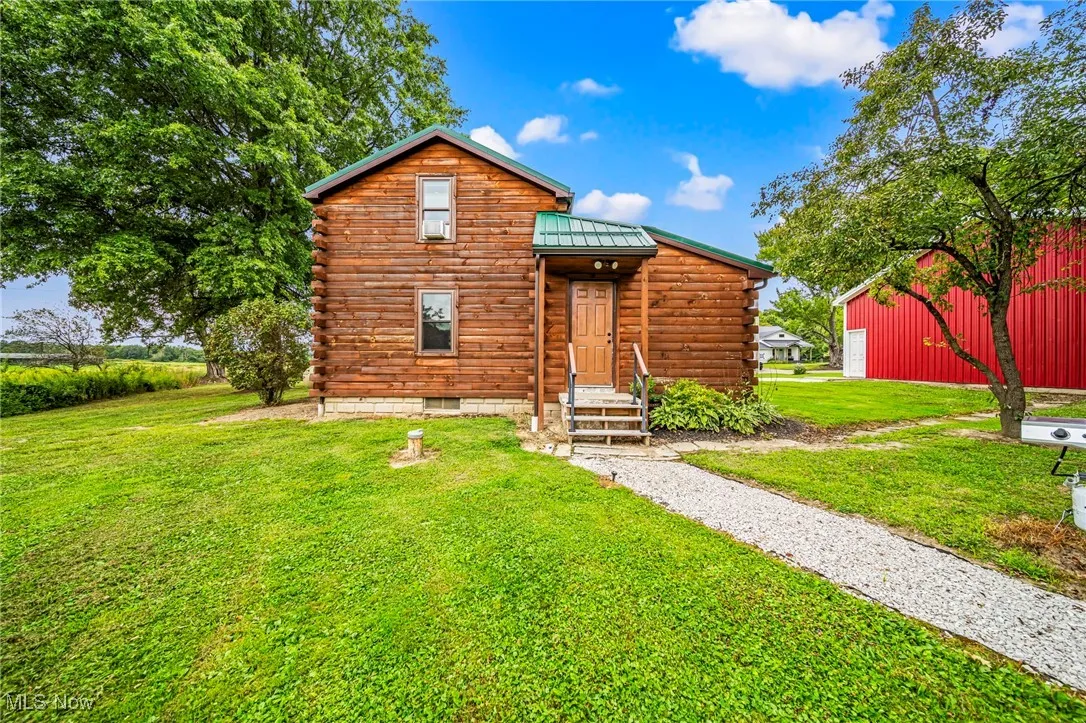 Log cabin featuring log siding, a front yard, a metal roof, and a standing seam roof