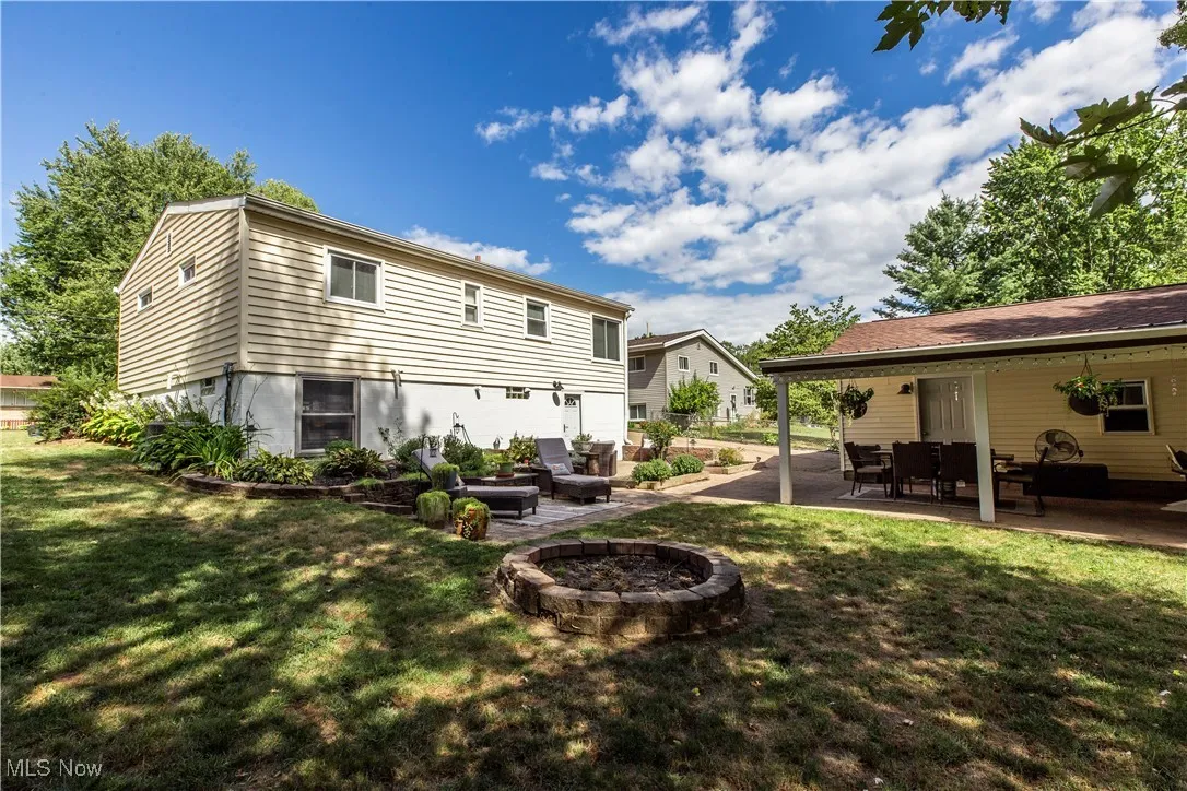 Back of house featuring a patio area, a lawn, and a fire pit