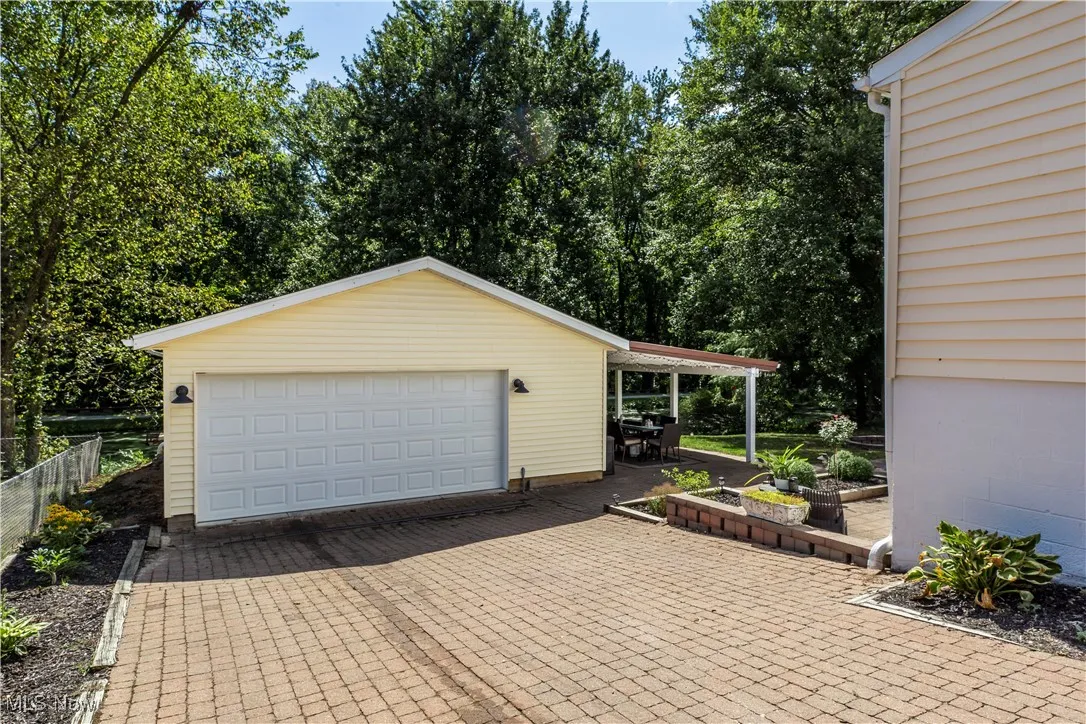 Detached garage featuring view of scattered trees