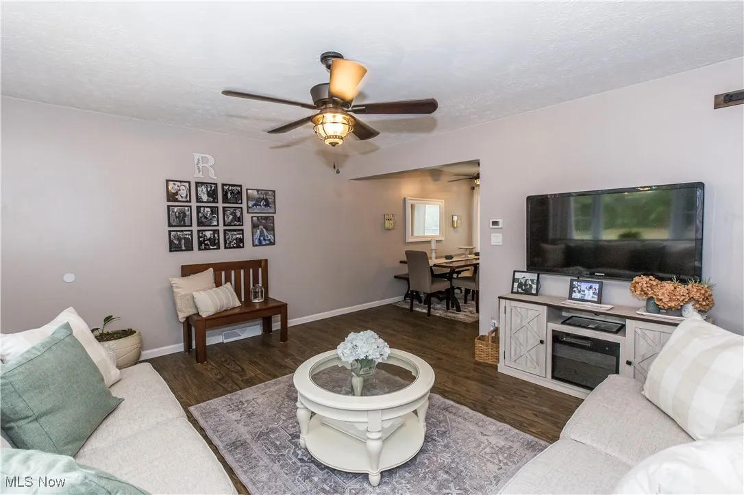 Living area featuring wood finished floors, a textured ceiling, and a ceiling fan