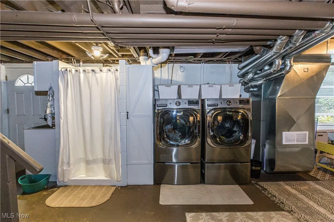 Laundry area featuring healthy amount of natural light, heating unit, and washing machine and clothes dryer