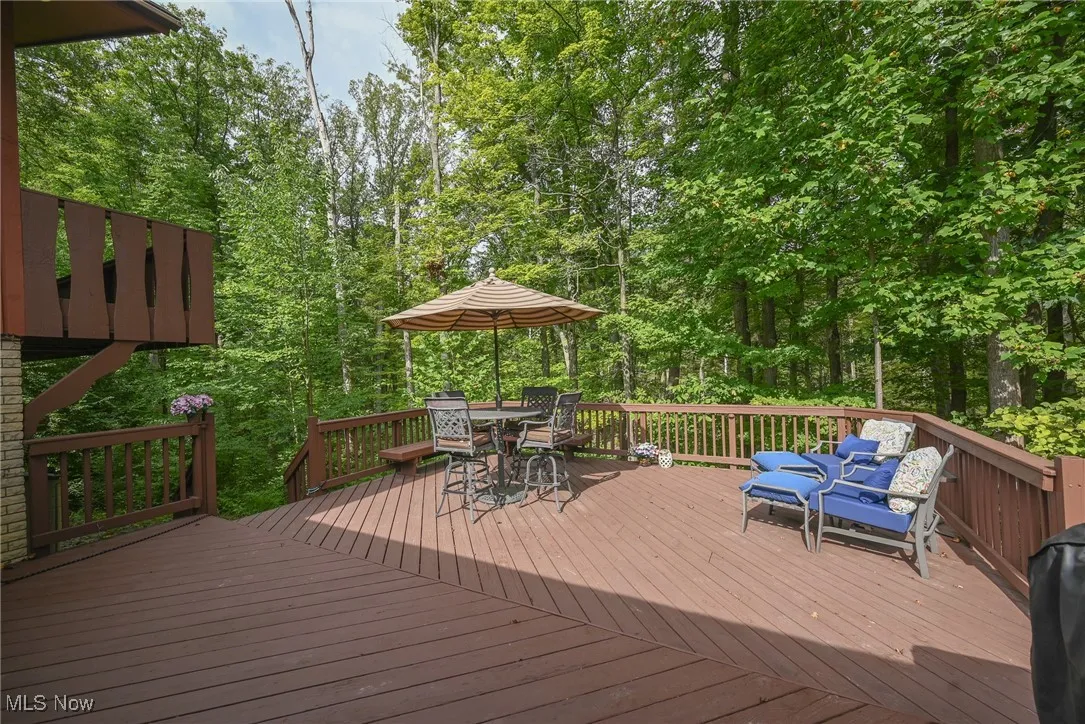 Deck with outdoor dining space and view of scattered trees
