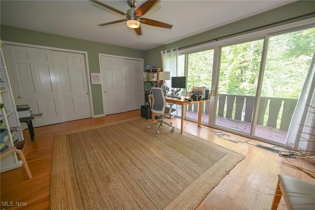 Office with light wood-type flooring and a ceiling fan