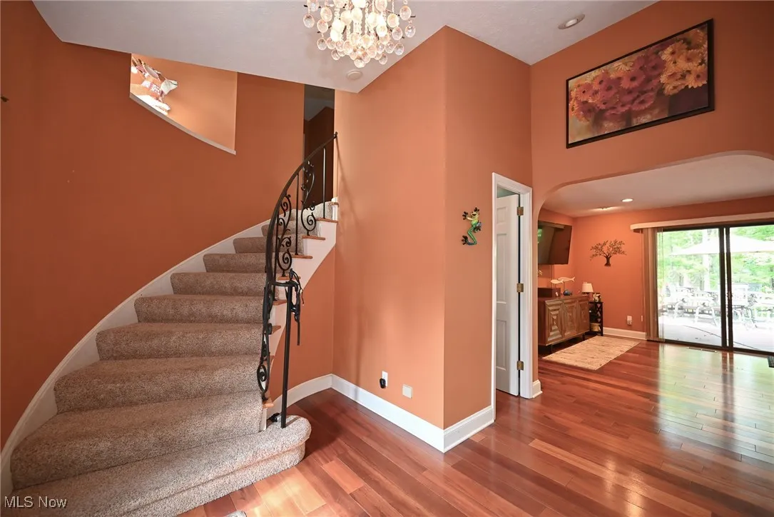 Stairway featuring wood finished floors, a chandelier, recessed lighting, a towering ceiling, and arched walkways