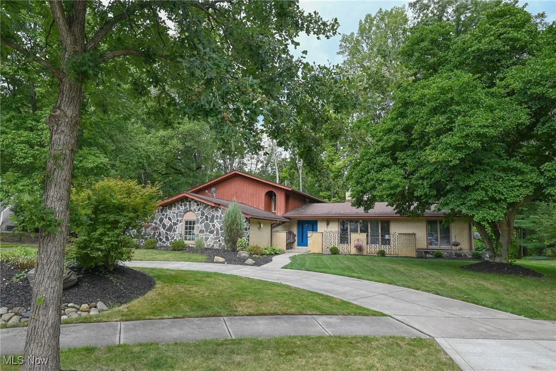 View of front of house featuring a front yard, brick siding, and view of wooded area