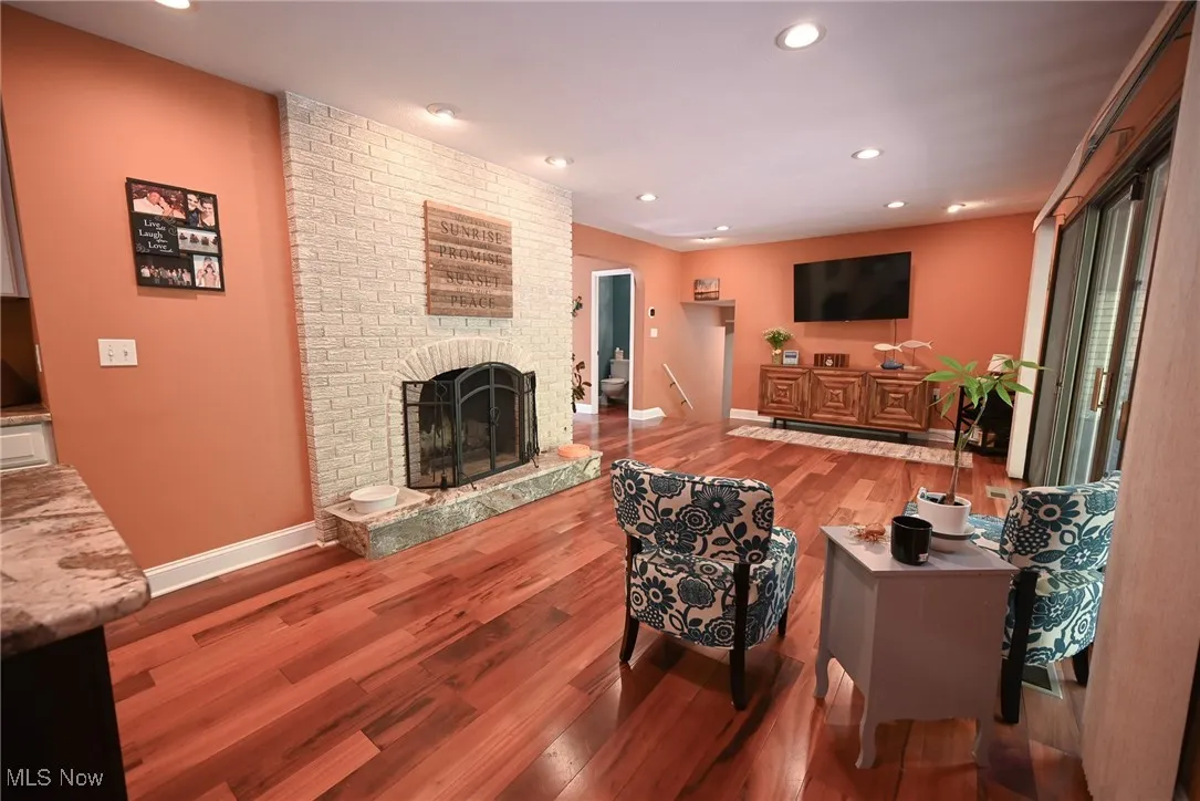 Living area with dark wood-type flooring, recessed lighting, and a fireplace