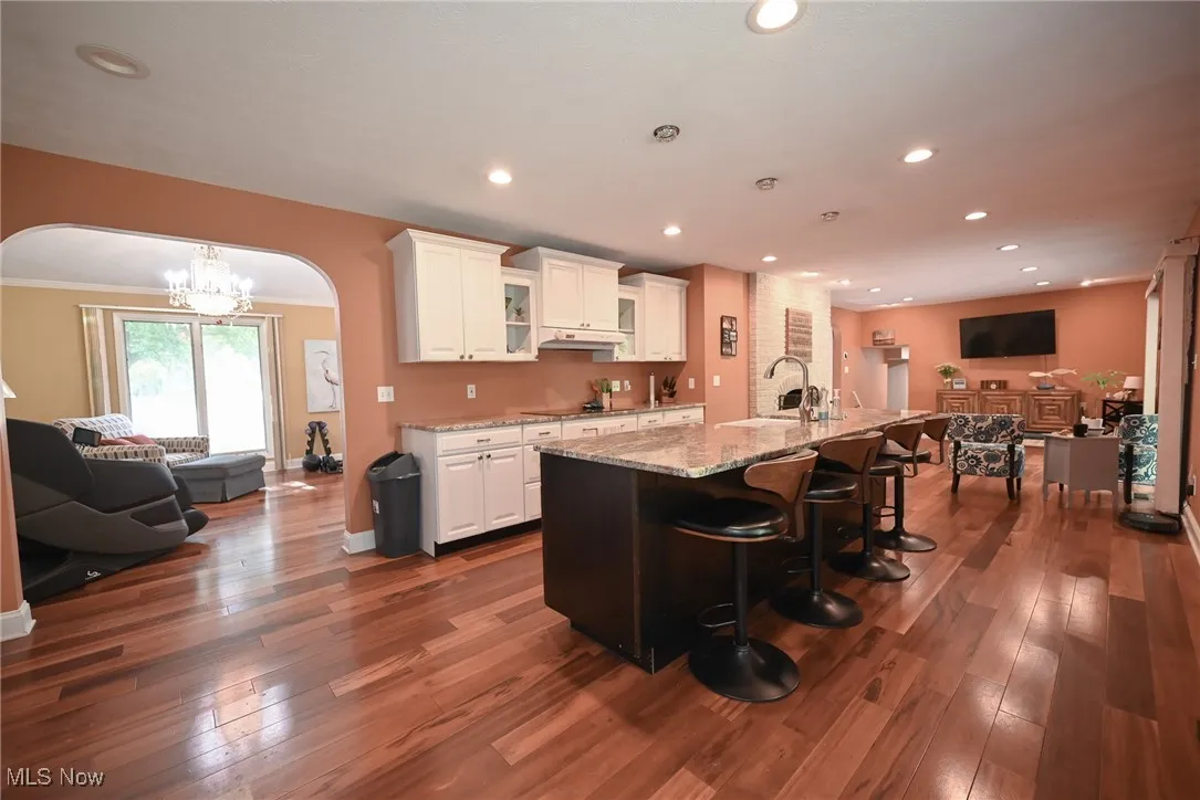 Kitchen featuring a chandelier, a kitchen breakfast bar, glass insert cabinets, open floor plan, and arched walkways