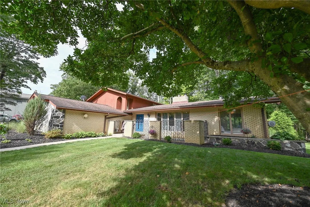 Tri-level home with a chimney, brick siding, and a front lawn