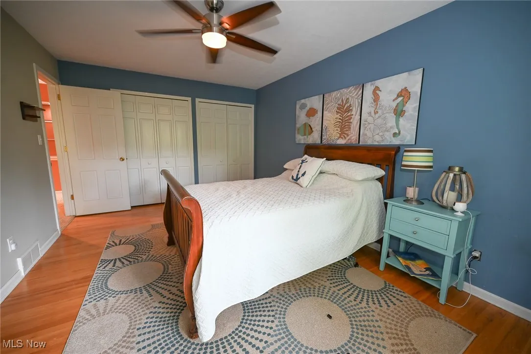 Bedroom featuring multiple closets, light wood-style flooring, and ceiling fan