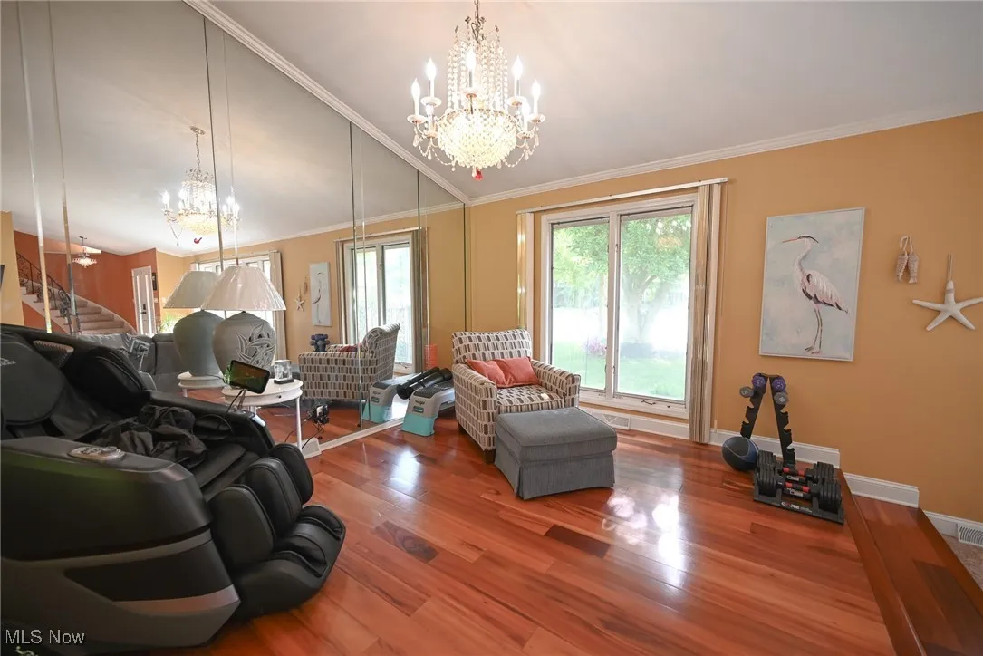 Living room featuring a chandelier, ornamental molding, wood finished floors, stairs, and vaulted ceiling