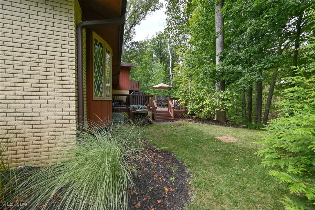 View of green lawn featuring a wooden deck