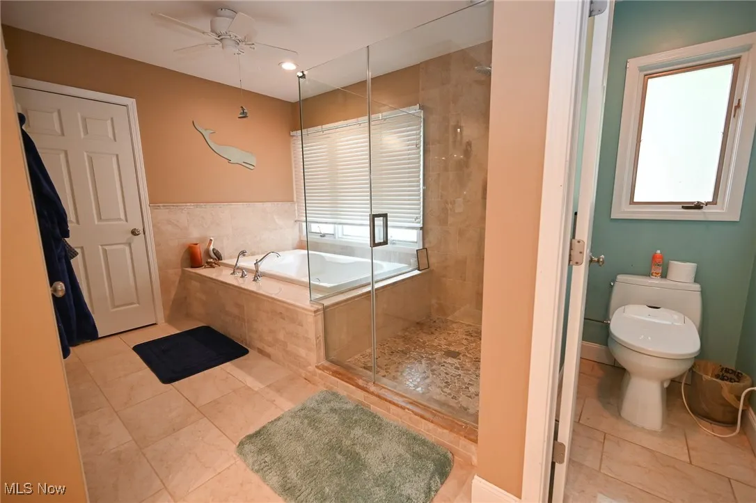 Bathroom with a bath, a shower stall, tile patterned floors, and a ceiling fan