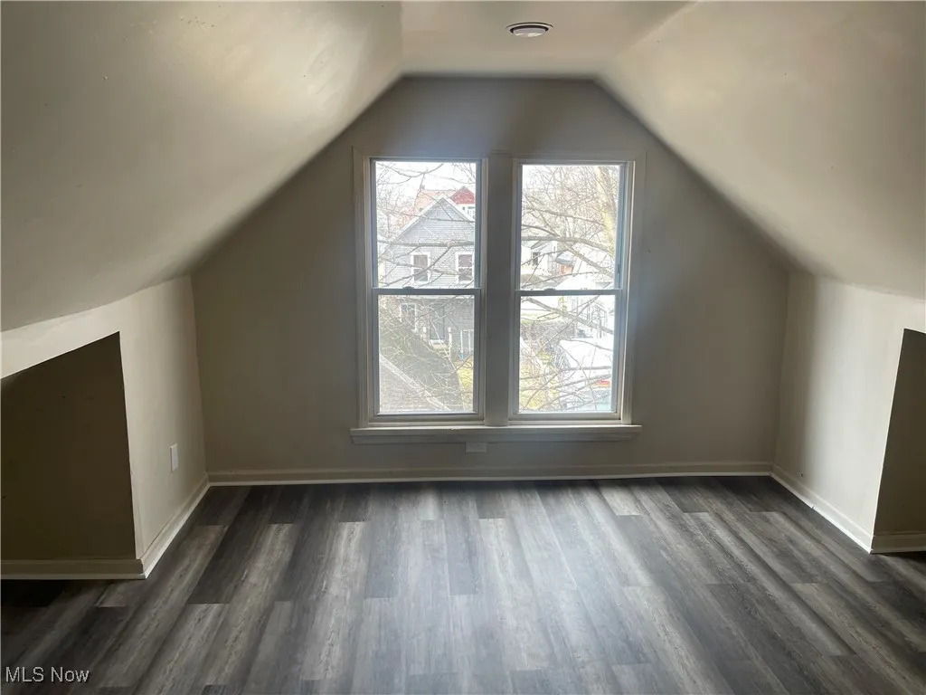 Bonus room featuring dark wood-style floors and vaulted ceiling