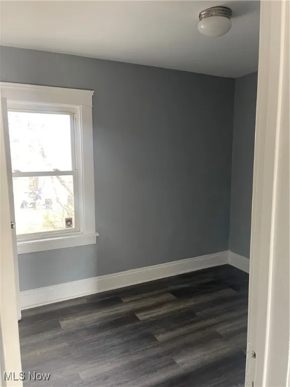 Empty room with dark wood finished floors and baseboards