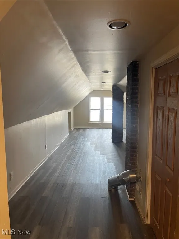 Additional living space featuring vaulted ceiling and dark wood-style flooring