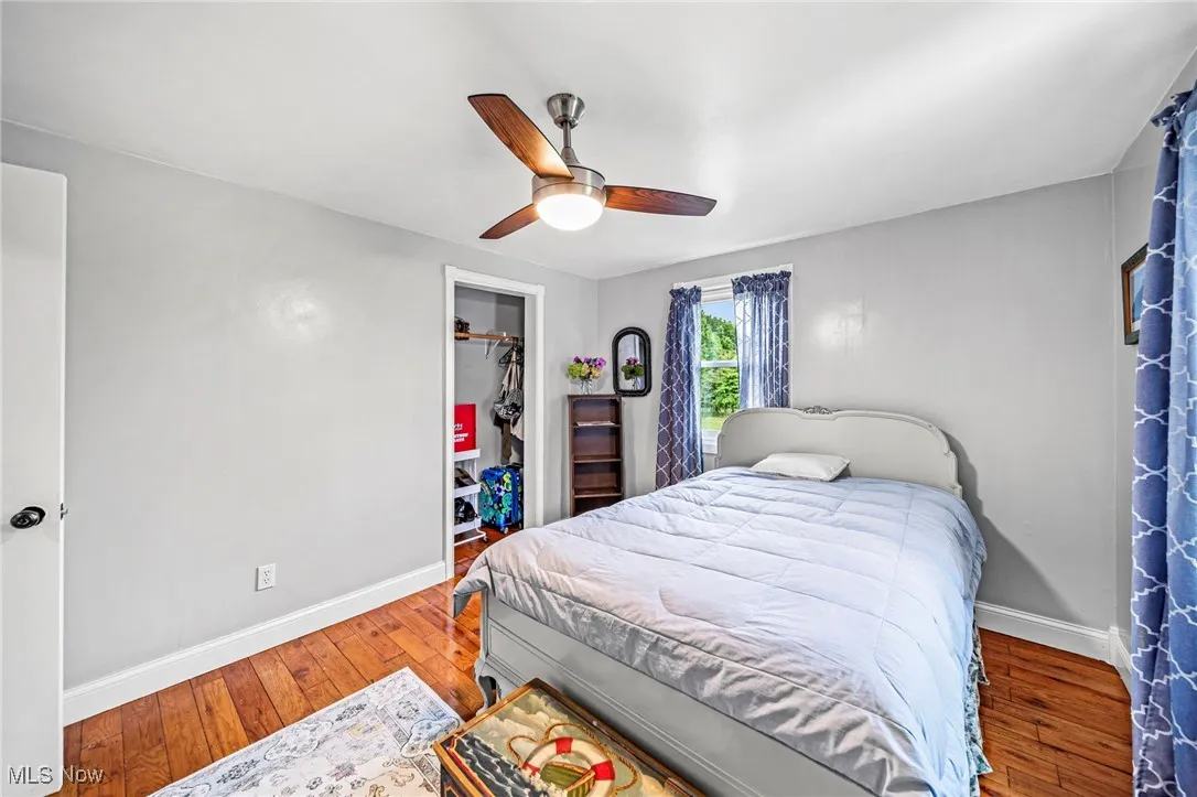 Bedroom with hardwood / wood-style floors, a ceiling fan, and a closet