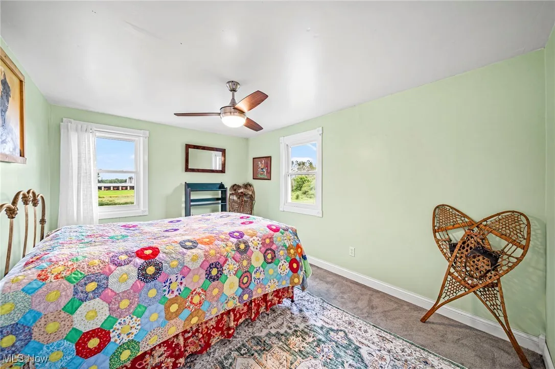 Bedroom with carpet, multiple windows, and ceiling fan