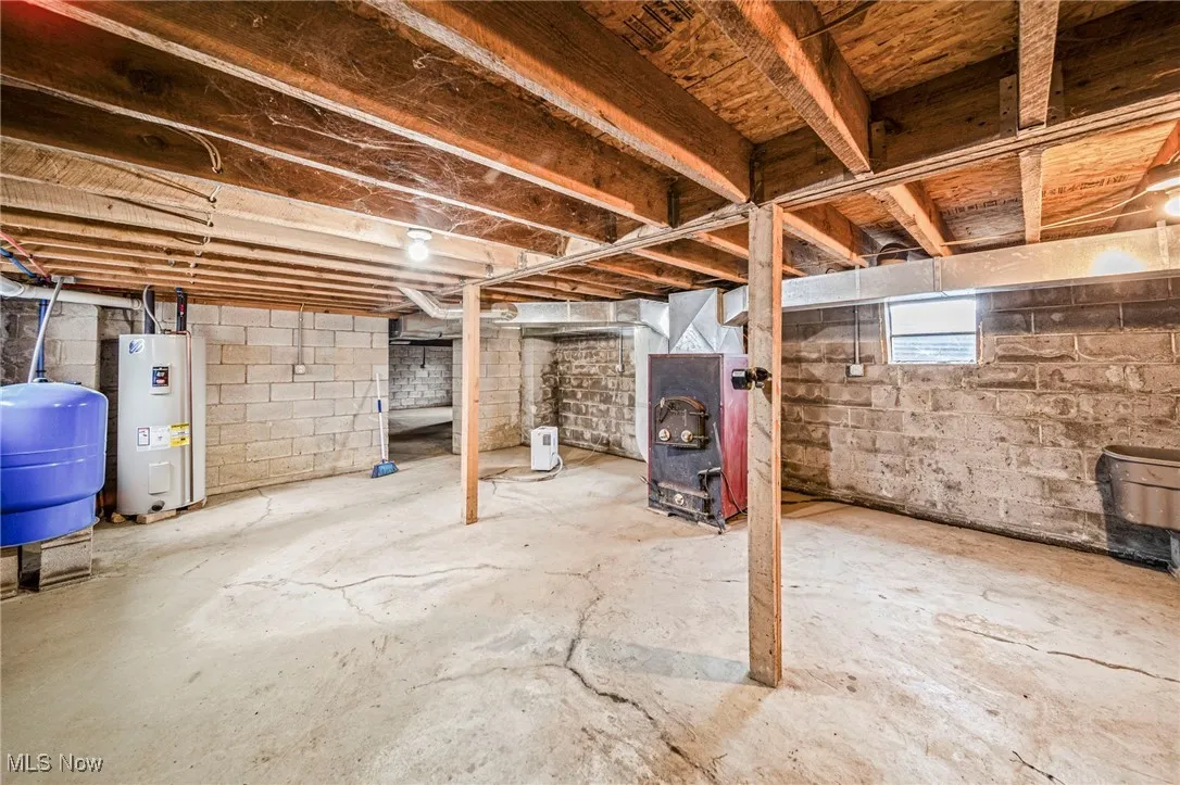 Basement featuring a water pressure tank, electric water heater, and heating unit