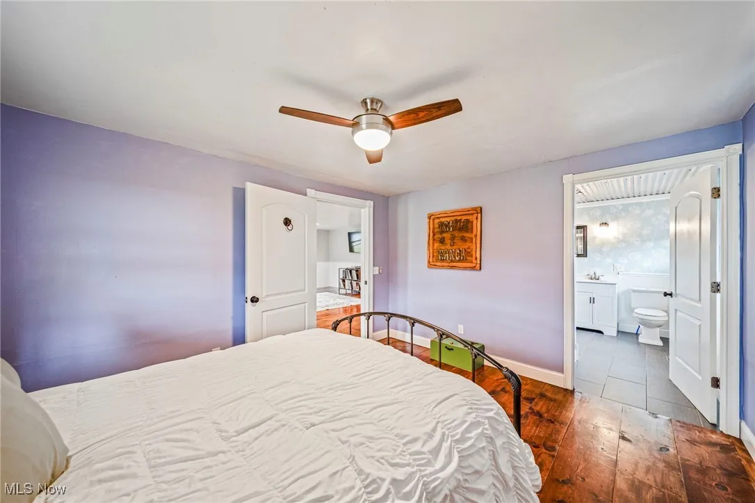 Bedroom with hardwood / wood-style flooring, a ceiling fan, and connected bathroom