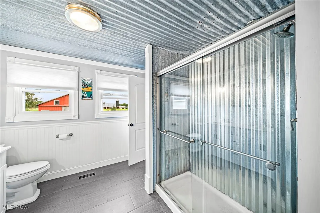 Bathroom featuring a shower stall, a wainscoted wall, and vanity
