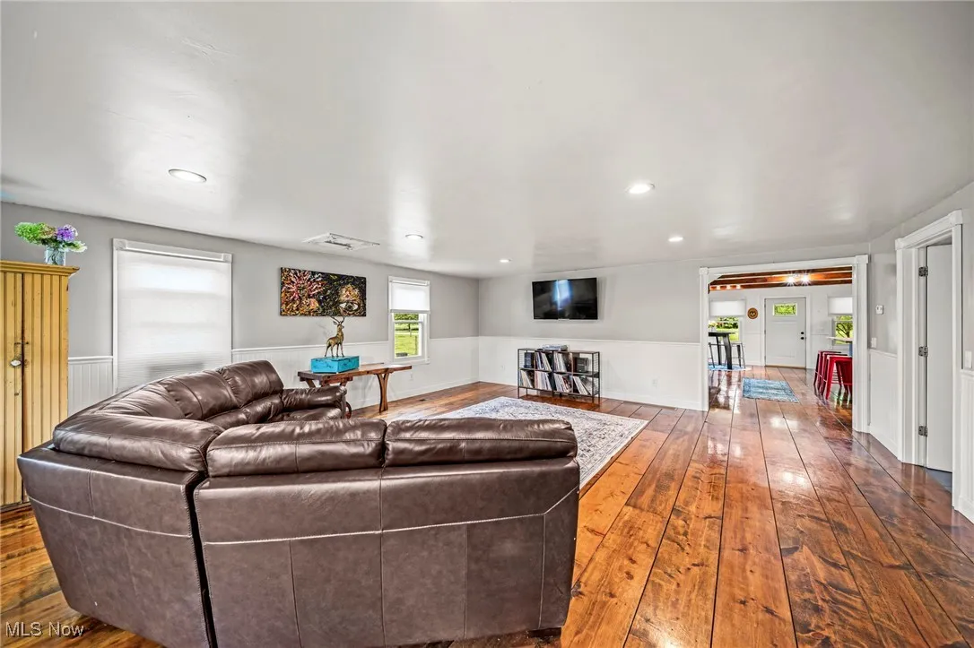 Living room featuring hardwood / wood-style floors, a wainscoted wall, and recessed lighting