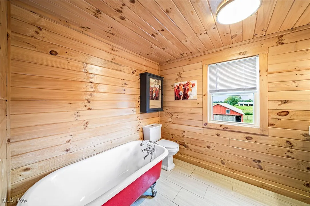 Full bath with a freestanding bath, wooden walls, and wood ceiling