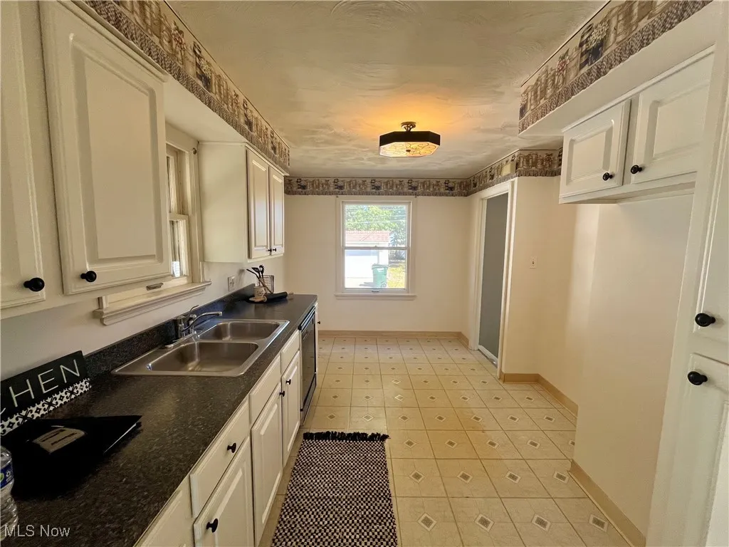 Kitchen featuring dark countertops, white cabinetry, and dishwashing machine