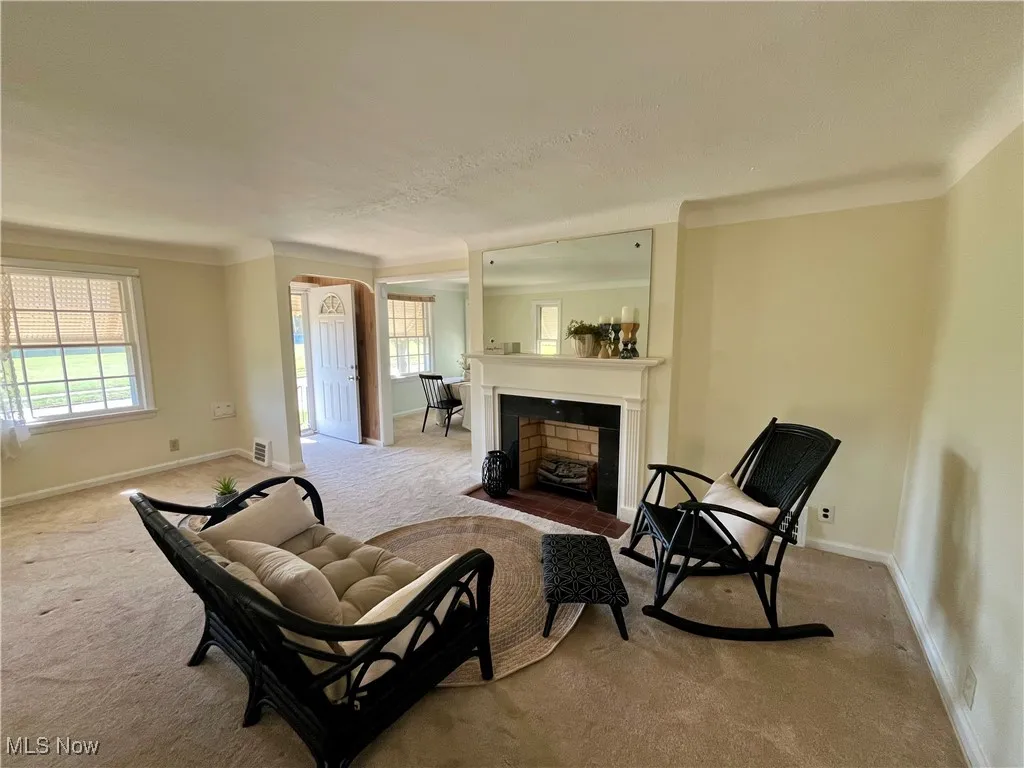 Sitting room featuring carpet flooring, a fireplace with flush hearth, and crown molding