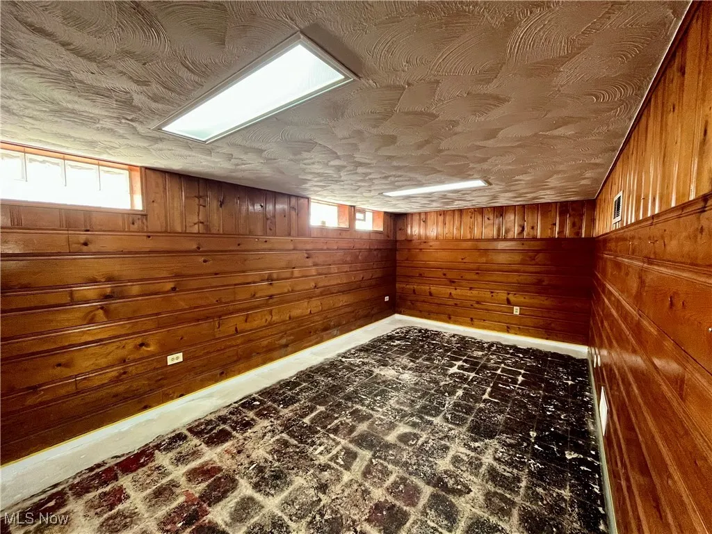 Bonus room with wood walls and brick flooring