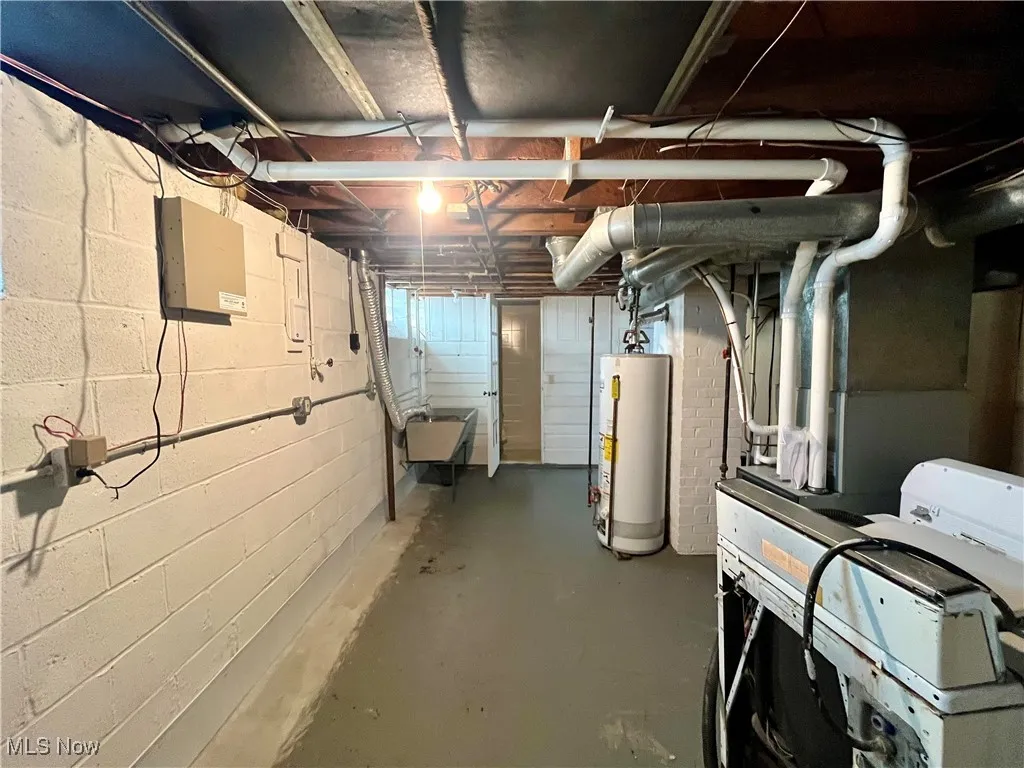 Unfinished basement featuring heating unit and gas water heater