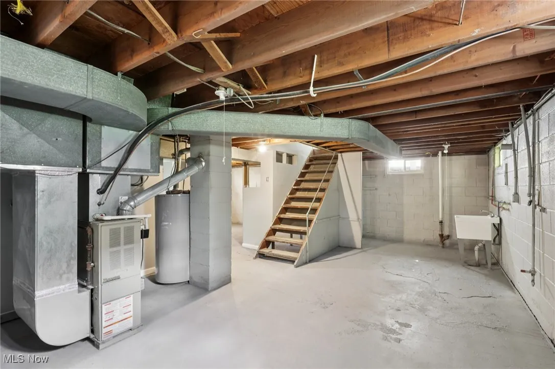 Basement with stairway, water heater, and heating unit