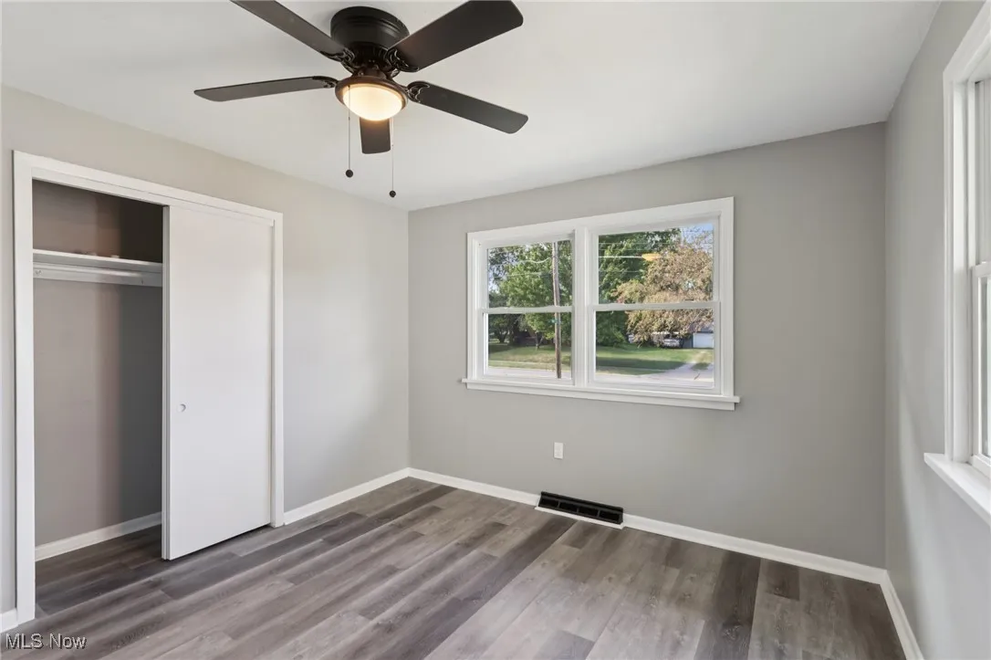 Unfurnished bedroom featuring dark wood-type flooring, a ceiling fan, and a closet
