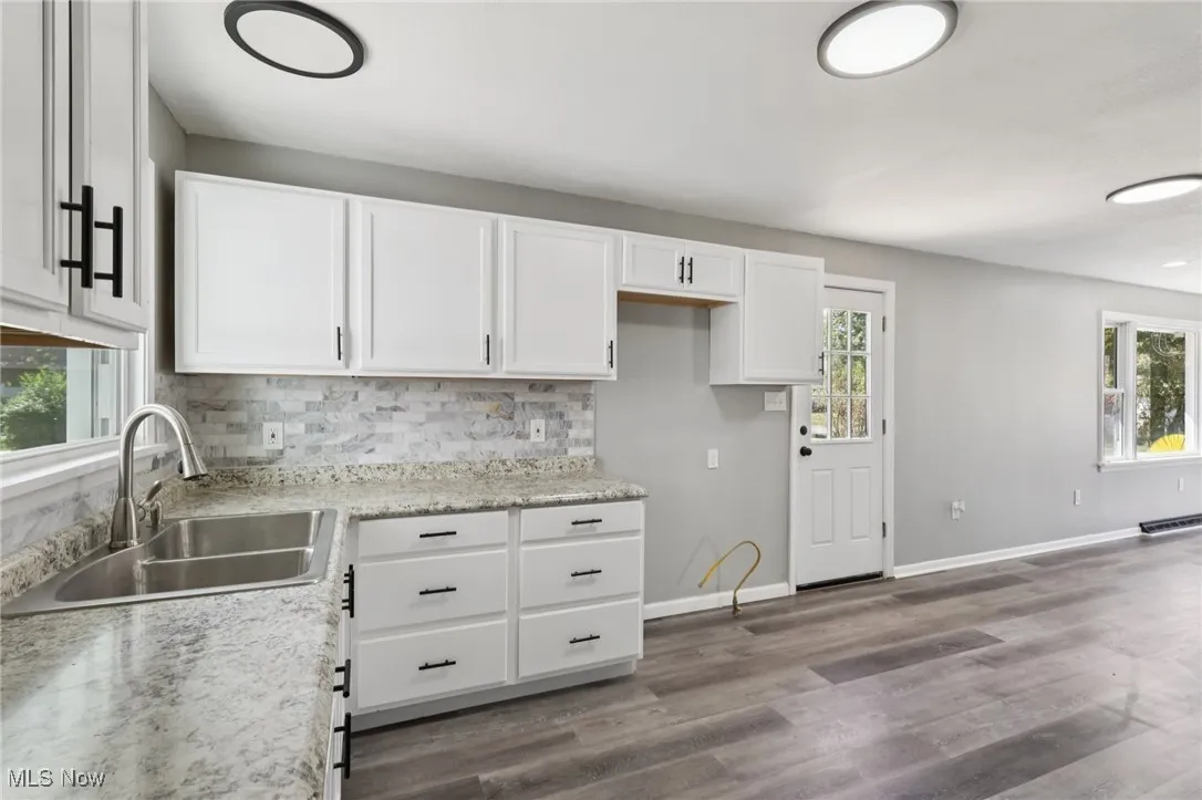Kitchen featuring white cabinets, backsplash, and dark wood-style floors