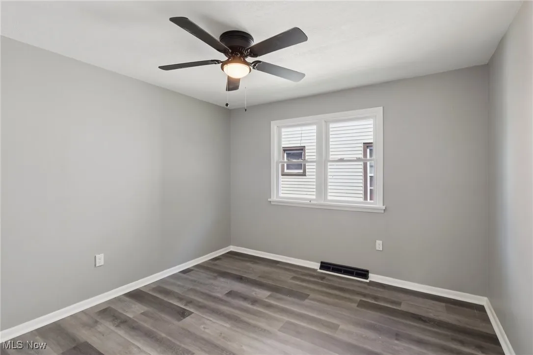 Spare room featuring dark wood finished floors and ceiling fan