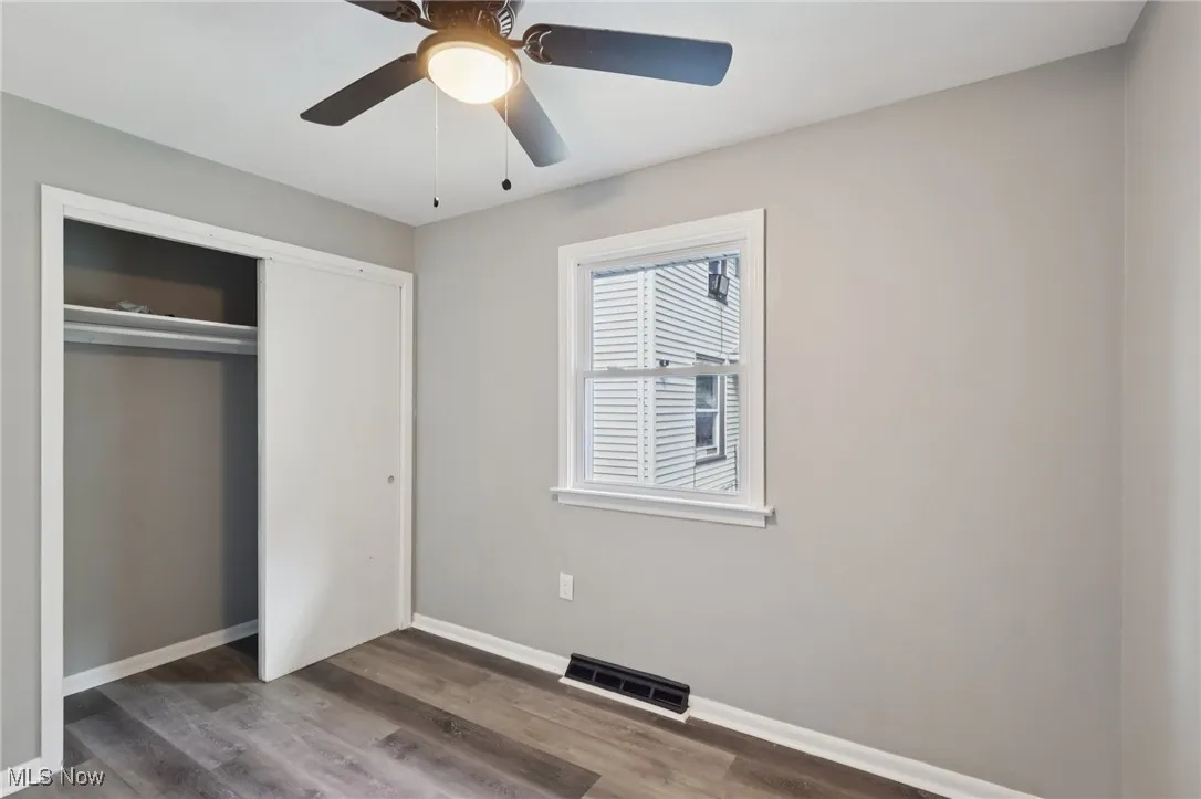 Unfurnished bedroom with dark wood-type flooring, a ceiling fan, and a closet