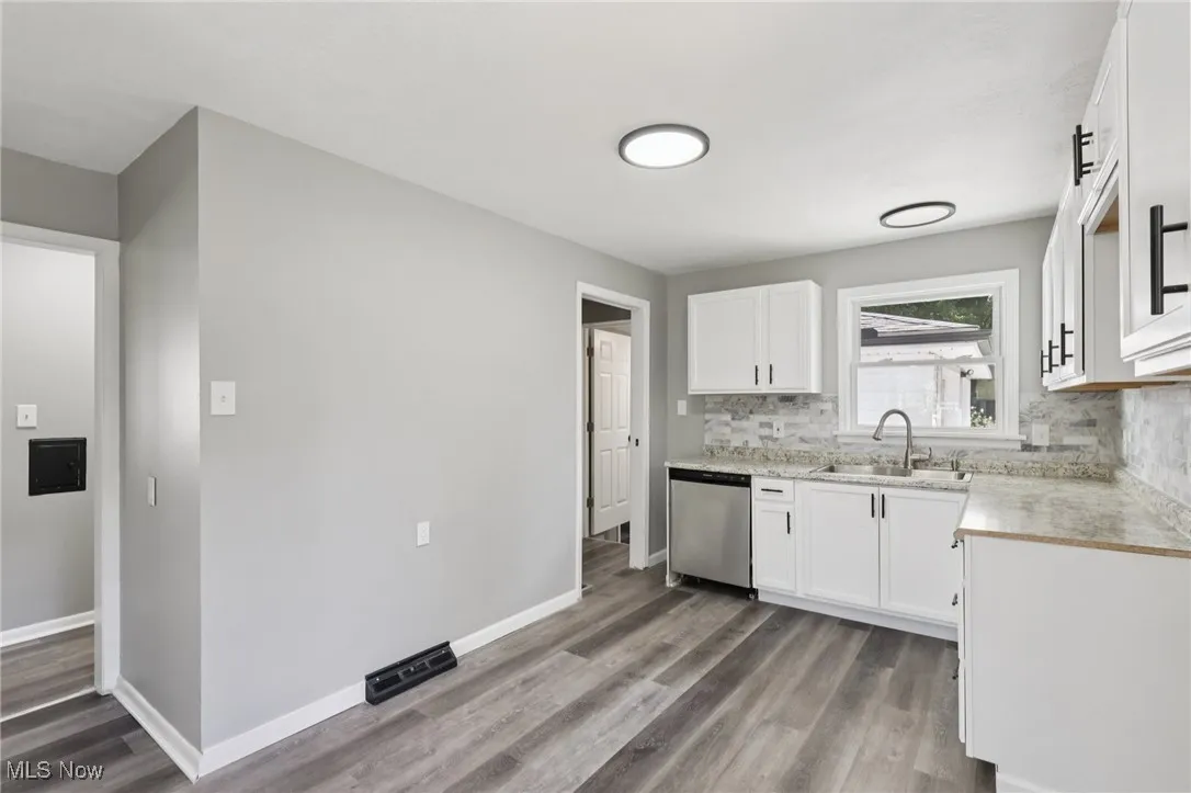 Kitchen featuring light countertops, white cabinets, light wood finished floors, dishwasher, and backsplash