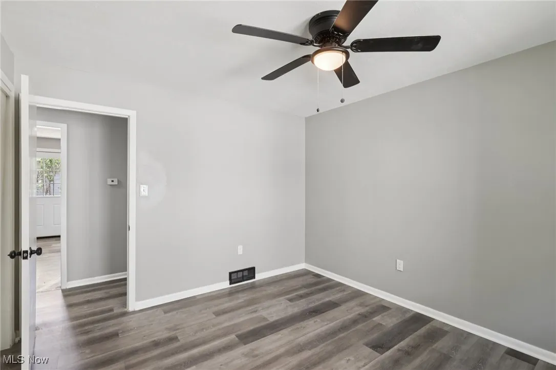 Unfurnished room featuring dark wood-style flooring and a ceiling fan