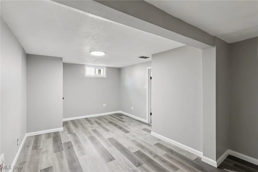 Below grade area with light wood finished floors and a textured ceiling