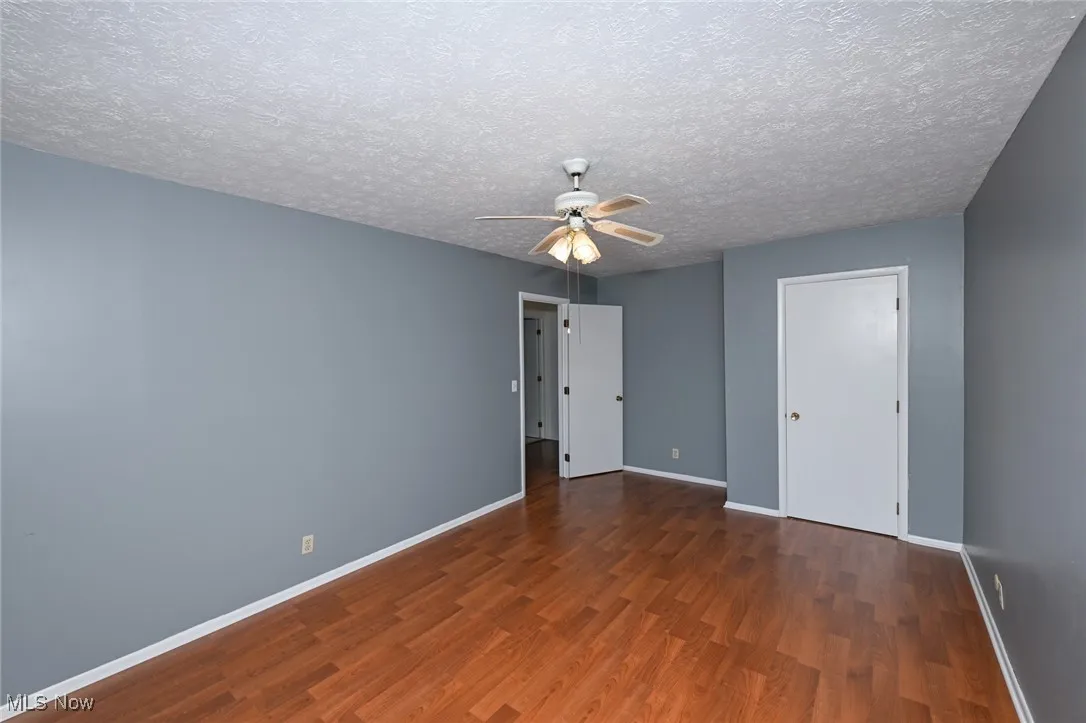 Upstairs bedroom #2 featuring dark wood finished floors, ceiling fan, and a textured ceiling