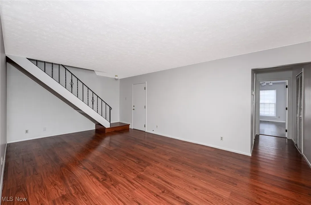 Living room with dark wood-style flooring, stairway, and a textured ceiling