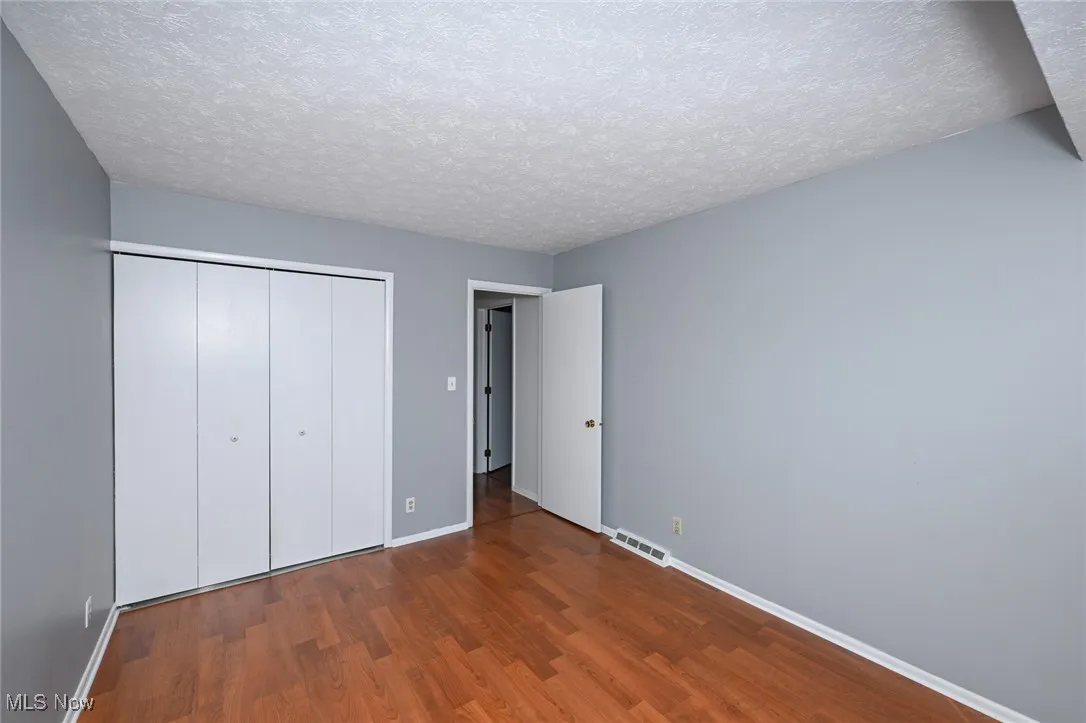 Upstairs bedroom #3 with wood finished floors, a closet, and a textured ceiling