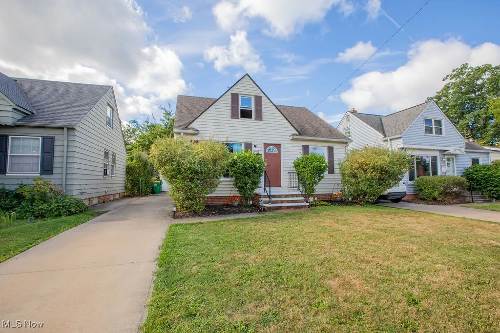 View of front of house featuring a front lawn, a shingled roof, and driveway