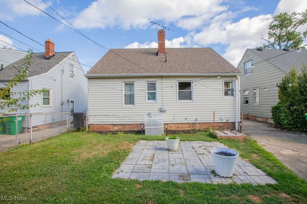 Back of house with a chimney, roof with shingles, and a patio area