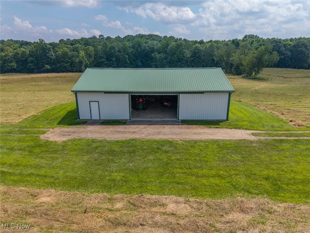 View of pole building featuring a yard, driveway, and a rural view