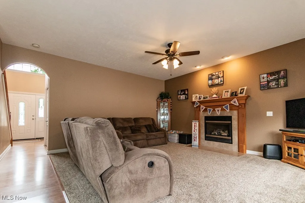 Living area featuring a tiled fireplace and ceiling fan