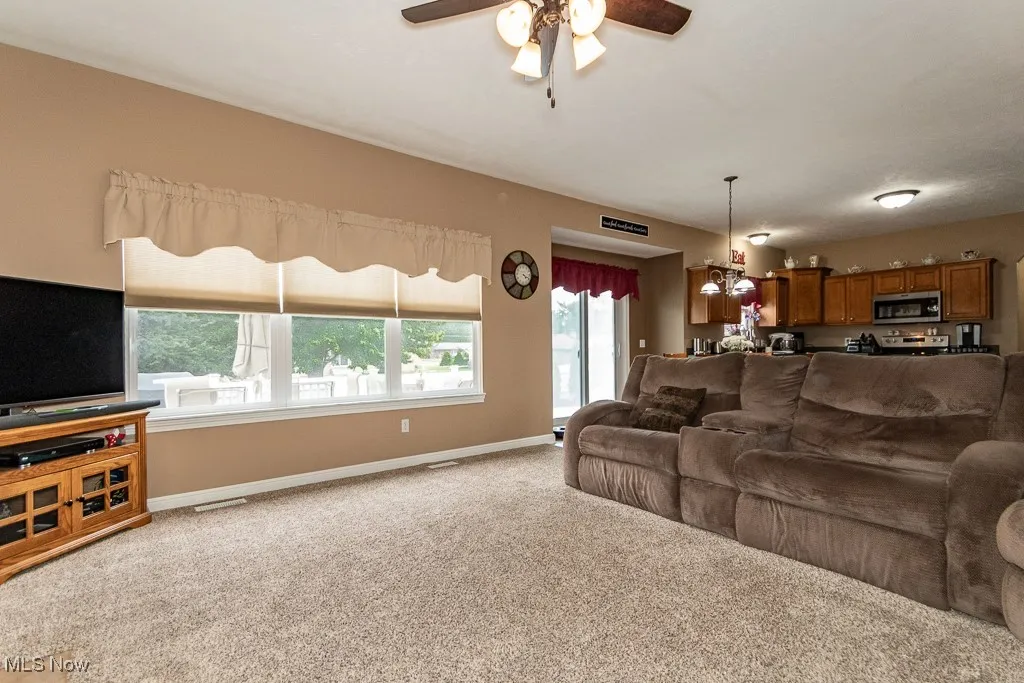Living room with light carpet, ceiling fan, and a chandelier