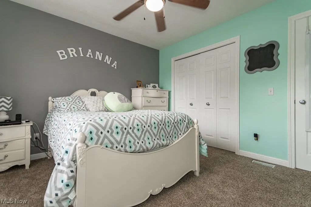 Bedroom with dark colored carpet, a closet, and a ceiling fan