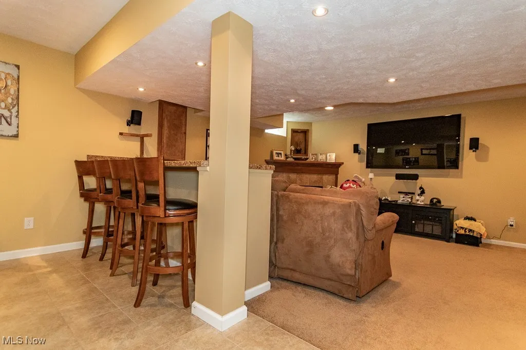 Living room with a dry bar, a textured ceiling, recessed lighting, and light colored carpet